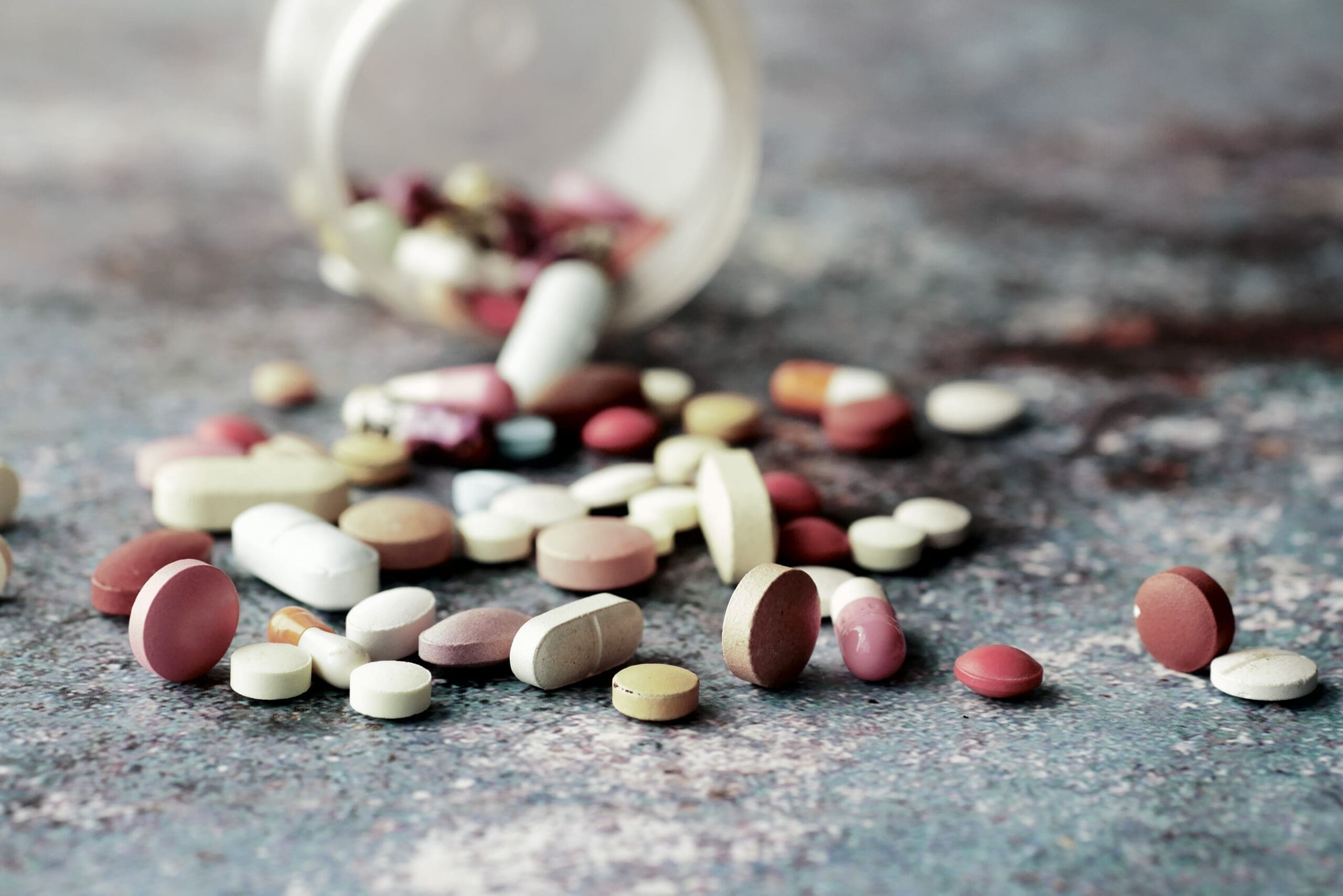 Various prescription pills spilled from a container, representing the process of Drug Detox vs Drug Rehab in Tennessee.