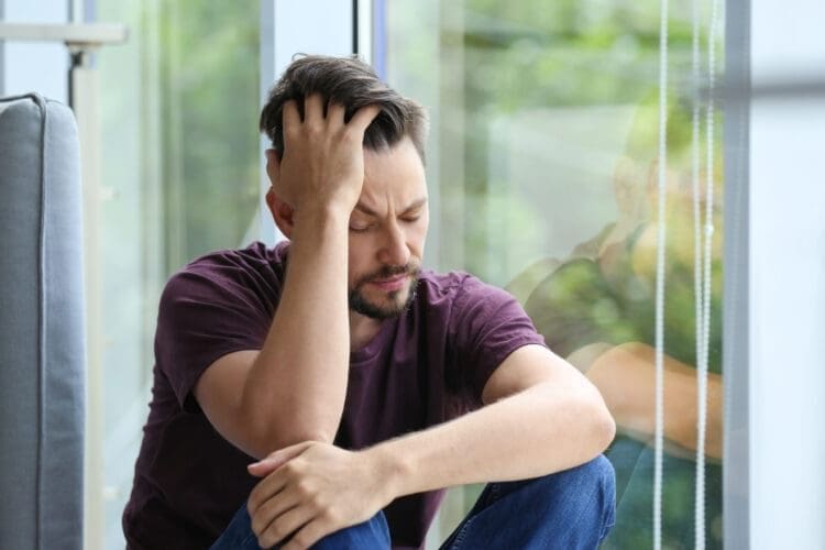 Man sitting by a window appearing distressed, representing the struggles of opioid addiction, emphasizing the importance of Fentanyl Rehab in Tennessee for recovery.